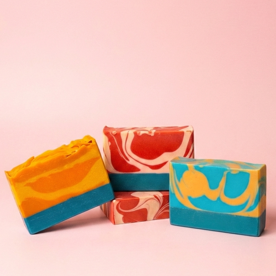 Three colorful soap bars with marbled patterns on a pink background