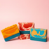 Three colorful soap bars with marbled patterns on a pink background